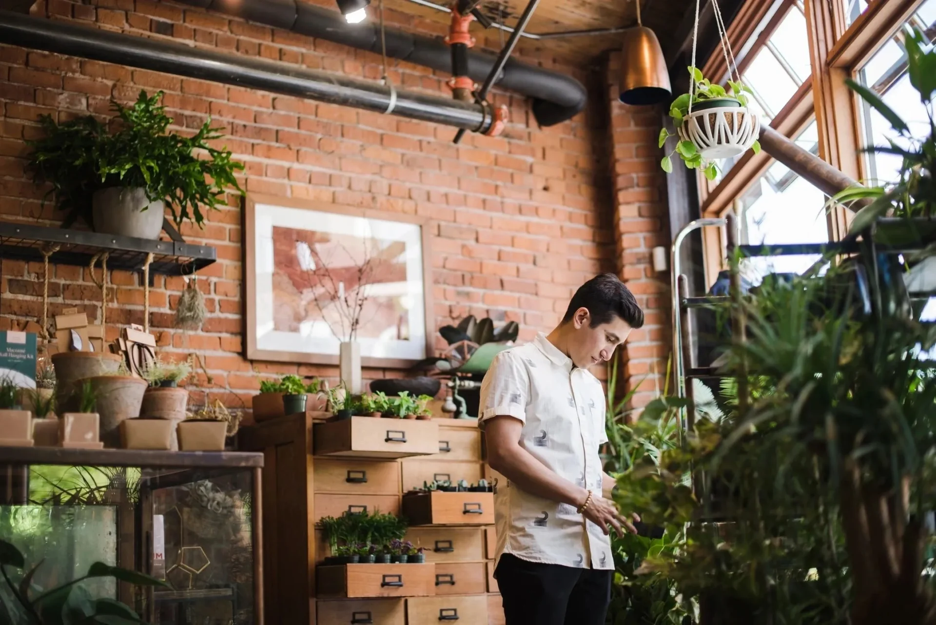 A man in white shirt standing next to plants.